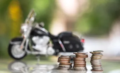 Des piles de pièces de monnaies posée devant une moto noire en arrière-plan