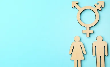 Symbole transgenre en bois au-dessus de figurines d'une femme et d'un homme