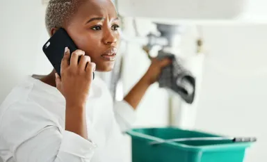 Femme au téléphone ayant des problèmes de pression d'eau dans son appartement