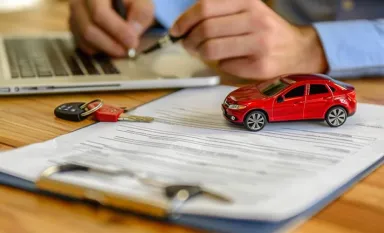 Une voiture miniature posée sur un contrat d'assurance auto