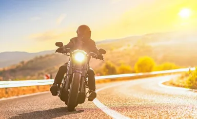 Un motard roulant sur la route au coucher du soleil