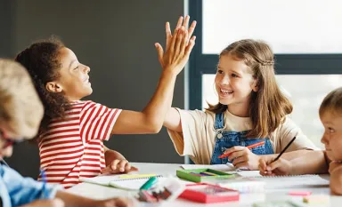 Deux fillettes à l'école se félicitant de leur réussite en se tapant dans la main