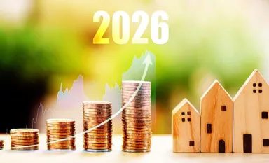 Des piles de pièces et des petites maisons en bois surmontées de l'année 2026