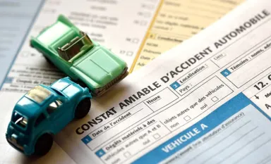 Deux voitures miniatures posés sur un exemplaire de constat amiable d'accident
