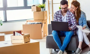 Un couple qui vient d'emménager regardant leur ordinateur portable 