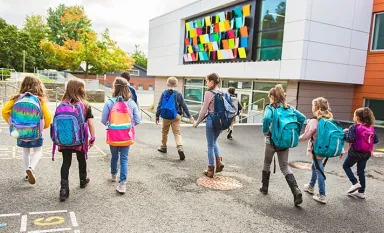 Un groupe d'enfants vus de dos allant à l'école 