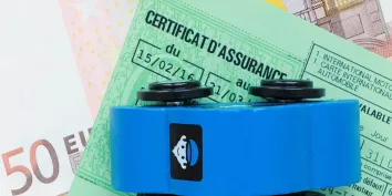 Une voiture miniature bleue posée sur une vignette verte d'assurance