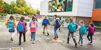 Un groupe d'enfants vus de dos allant à l'école 
