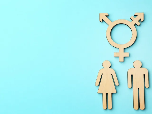 Symbole transgenre en bois au-dessus de figurines d'une femme et d'un homme