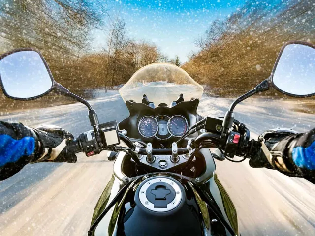 Moto vue du pilote sur une route enneigée
