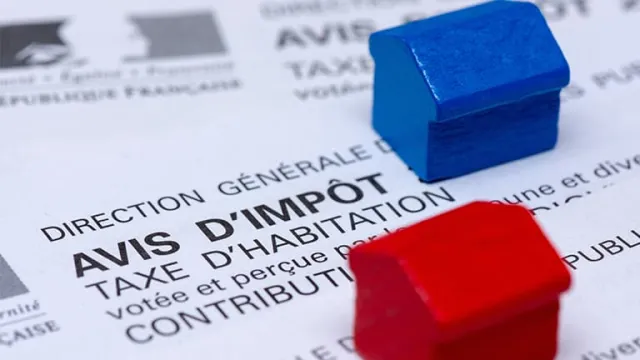 Deux maisons miniatures bleue et rouge posées sur un avis d'imposition de la taxe d'habitation