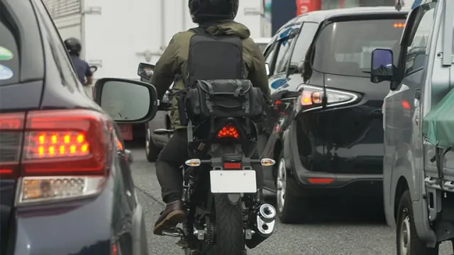 Un scooter circulant entre deux files de voitures