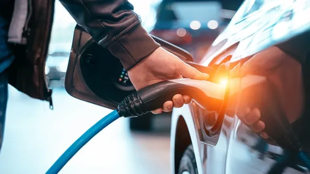 Une main d'homme tenant un câble pour charger sa voiture électrique