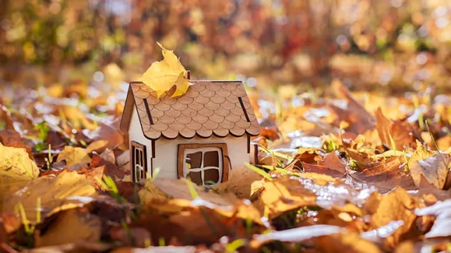 Une petite maison en bois posée sur des feuilles mortes