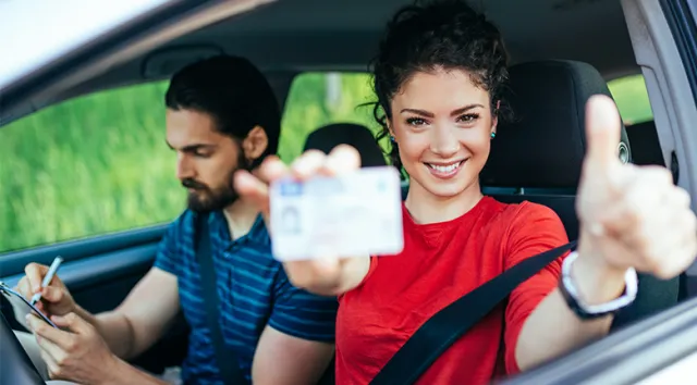 Une jeune fille avec un t-shirt rouge qui vient d'obtenir son permis de conduire