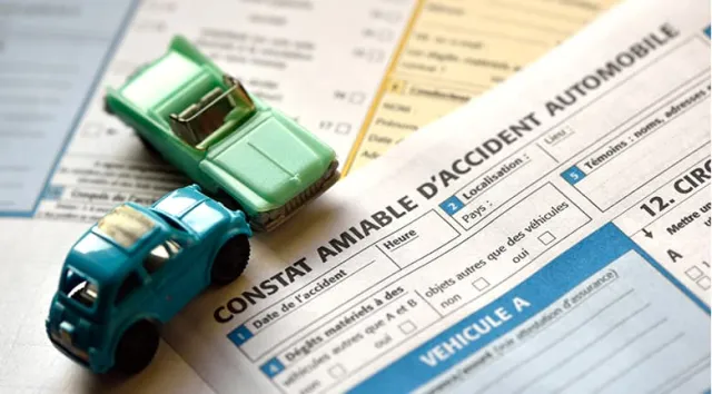 Deux voitures miniatures posés sur un exemplaire de constat amiable d'accident