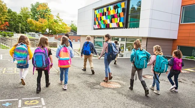 Un groupe d'enfants vus de dos allant à l'école 